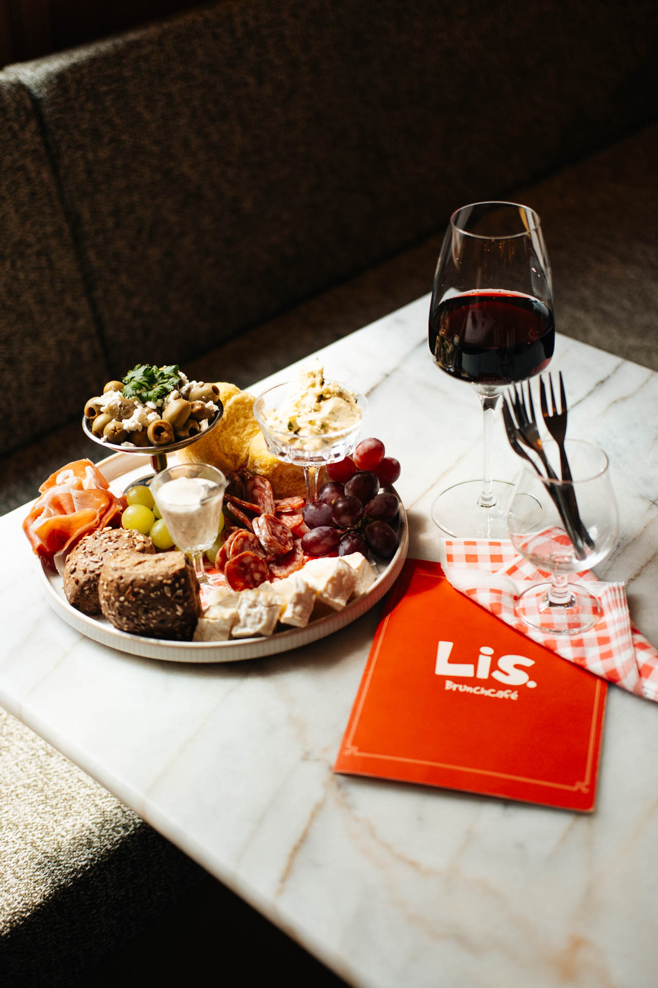 Charcuterieplank met rode wijn op marmeren tafel.